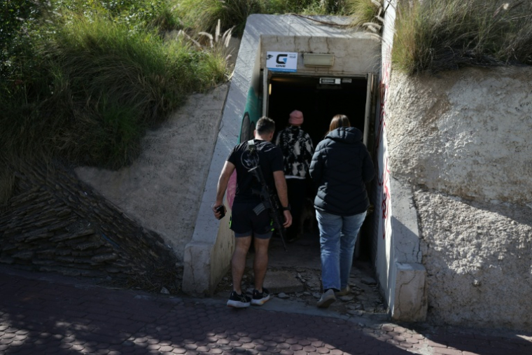 Des habitants entrent dans un abri après un tir de missile iranien, le 8 mars 2026 à Tel-Aviv  ( AFP / Ilia YEFIMOVICH )