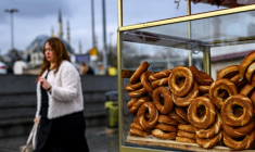 Une femme passe à côté d'un vendeur de simits, petits pains ronds turcs en forme d'anneau, le 27 décembre 2025 à Istanbul ( AFP / Yasin AKGUL )
