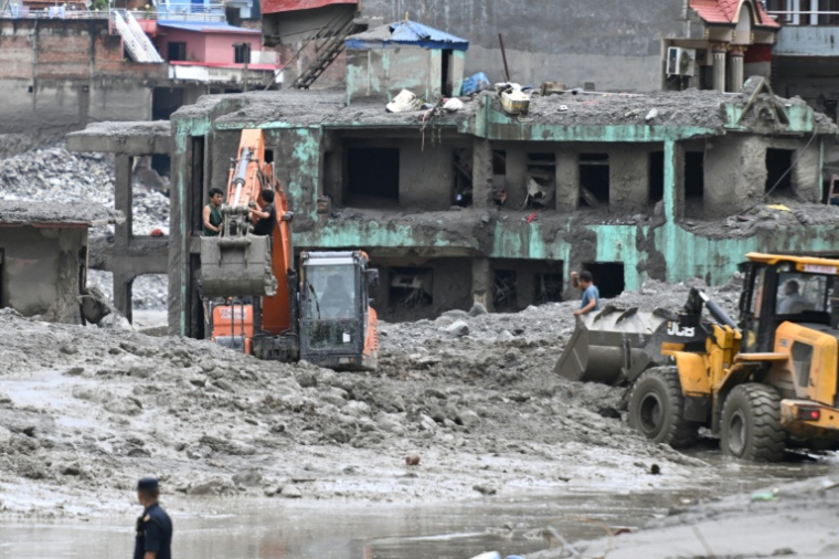 Une pelleteuse déblaie la boue et les gravats après la crue destructrice qui a fait plus de 600 morts à la frontière entre le Népal et la Chine, le 29 août 2026 à Trishuli, dans le district népalais de Nuwakot   ( AFP / Arun SANKAR )