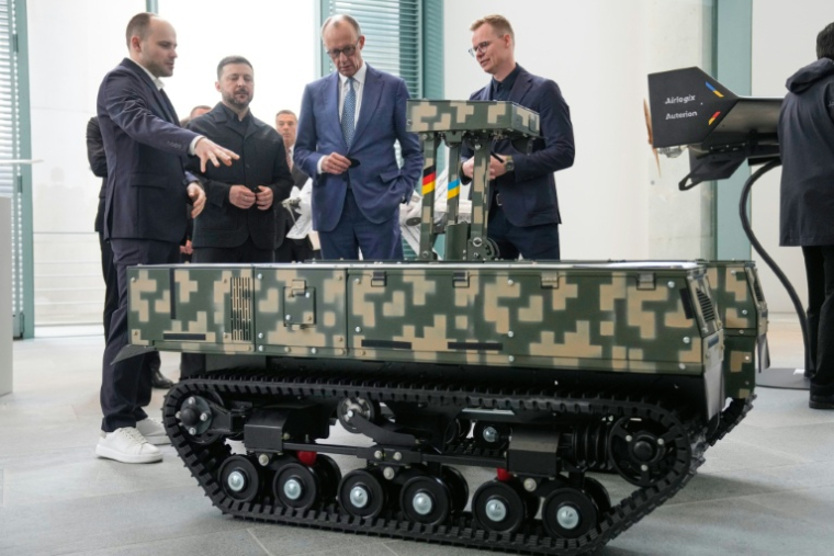 Le chancelier allemand Friedrich Merz (3e g) et le président ukrainien Volodymyr Zelensky (2e g) assistent à une présentation de drones issus de la coopération germano-ukrainienne, le 14 avril 2026 à Berlin ( POOL / Ebrahim Noroozi )