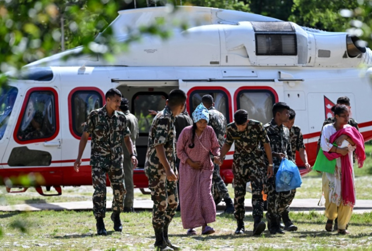Des militaires soutiennent une rescapée, au camp de Trishuli, dans le district de Nuwakot au Népal, le 28 août 2026 ( AFP / Arun SANKAR )