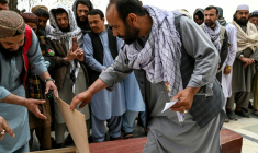 Abdul Hai Hamidi (c) regarde dans un cercueil à la recherche d'un proche lors des deuxièmes funérailles collectives des victimes tuées par une frappe aérienne pakistanaise sur un hôpital pour toxicomanes, à la mosquée Eid Gah de Kaboul le 26 mars 2026 en Afghanistan ( AFP / Wakil KOHSAR )