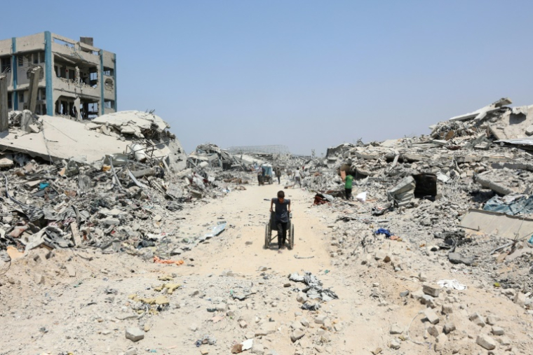 Un garçon palestinien tire un fauteuil roulant au milieu des dstructions dans le quartier al-Touffah de la ville de Gaza, le 14 août 2025 ( AFP / Omar AL-QATTAA )