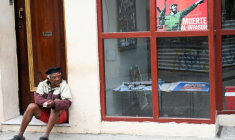 Un homme est assis non loin d'une affiche représentant l'ancien dirigeant cubain Fidel Castro (1926-2016) dans une rue de La Havane, le 16 février 2026 ( AFP / YAMIL LAGE )