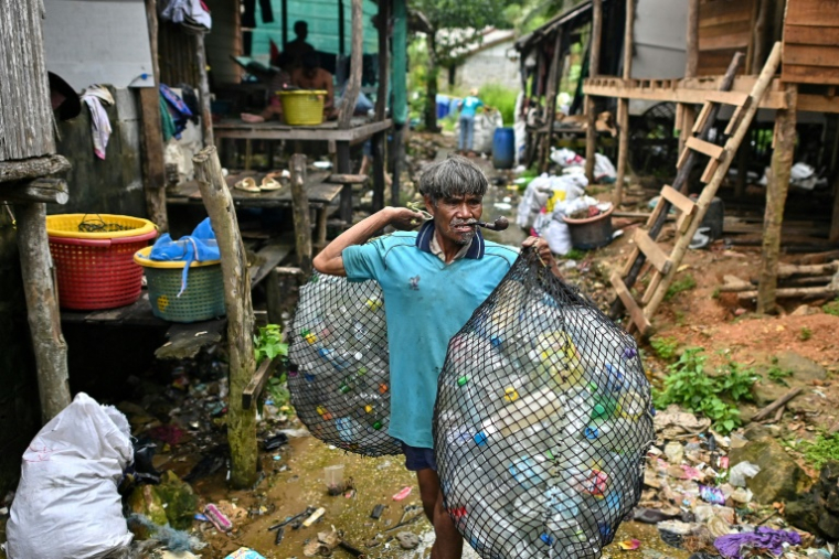 En Thailande, sur l'île de Koh Chang, un pêcheur montre un sac de déchets plastiques qu'il s'apprête à vendre à une ONG qui produit des granulés de plastique recyclé,le 24 septembre 2024 (ARCHIVES) ( AFP / MANAN VATSYAYANA )