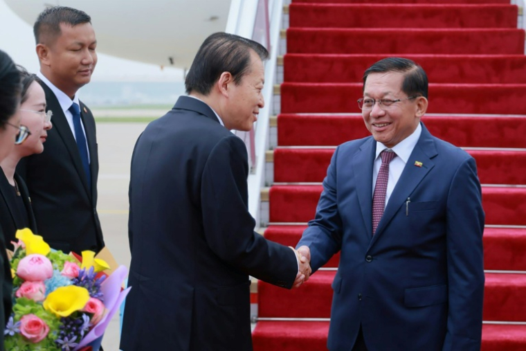 Photo diffusée le 15 juin 2026 par le Bureau de presse et d'information de la présidence birmane, montrant le président birman Min Aung Hlaing (d) accueilli par un responsable chinois à son arrivée à Pékin ( Bureau de presse et d'information de la présidence birmane / Handout )