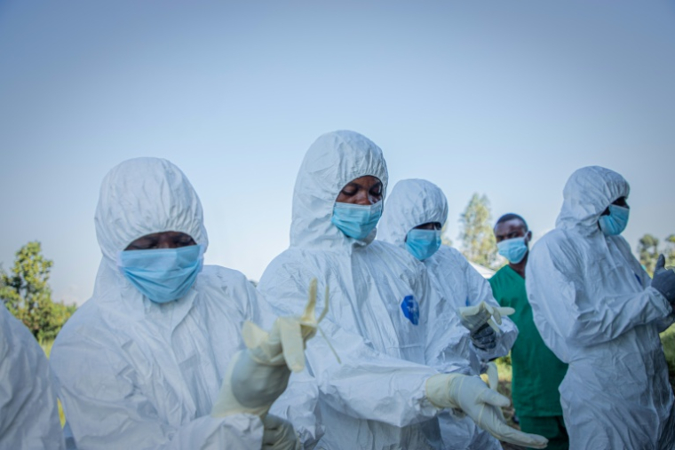 Des volontaires enfilent leurs équipements de protection avant de récupérer le corps d'un enfant de 3 ans, présumé mort du virus Ebola, le 11 juin 2026 à Bunia, en RDC  ( AFP / Benediction MURHABAZI )