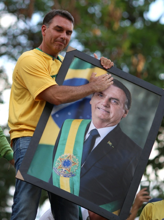 Le candidat à la présidentielle brésilienne Flavio Bolsonaro tient un portrait de son père, l'ex-président Jair Bolsonaro, devant ses soutiens à Goiania, au Brésil, le 27 septembre 2026 ( AFP / Sergio Lima )