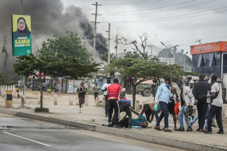 Des manifestants aident l'un d'entre eux, blessé, près de barricades en feu, le 29 octobre 2025 à Dar es Salaam, capitale économique de la Tanzanie ( AFP / - )