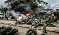 Un policier kényan déplace des pneus bloquant un axe routier, le 7 juillet 2025 à Nairobi ( AFP / Luis TATO )