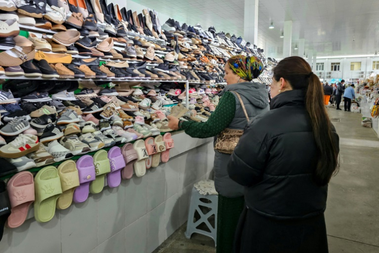 Une femme examine des chaussures fabriquées en Iran sur un marché d'Achkhabad, la capitale du Turkménistan, le 9 mars 2026 ( AFP / STRINGER )