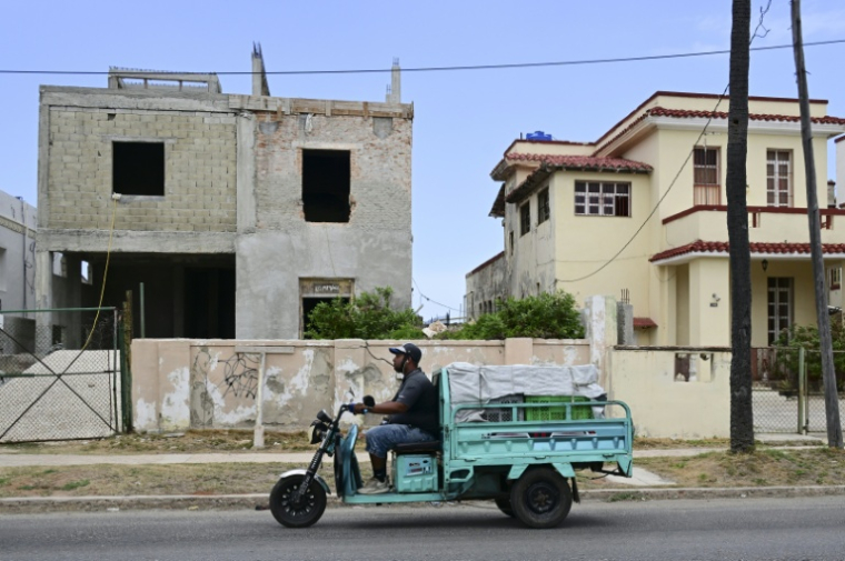 Un triporteur passe devant une maison en travaux à La Havane, le 23 avril 2026 ( AFP / YAMIL LAGE )