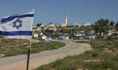 Israeli flags line the road leading to the Palestinian village of Umm al-Khair wedged between the new Jewish outpost of Karmel (foreground Left) and the Israeli settlement of Karmel (hilltop), south of the town of Yatta in the southern area of the Israeli-occupied Palestinian West Bank on April 14, 2026. ( AFP / HAZEM BADER )
