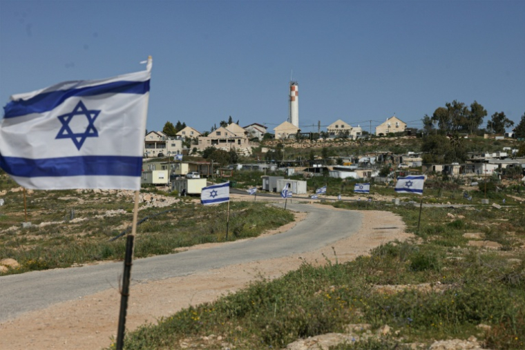 Israeli flags line the road leading to the Palestinian village of Umm al-Khair wedged between the new Jewish outpost of Karmel (foreground Left) and the Israeli settlement of Karmel (hilltop), south of the town of Yatta in the southern area of the Israeli-occupied Palestinian West Bank on April 14, 2026. ( AFP / HAZEM BADER )