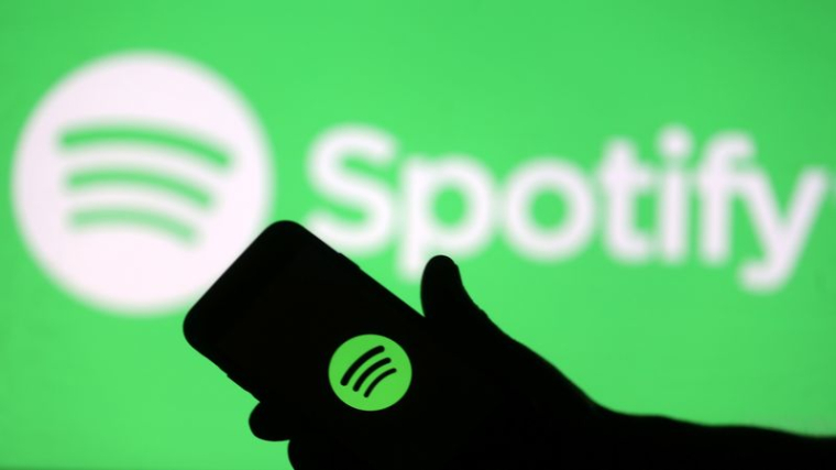 Un smartphone devant un écran projetant le logo de Spotify