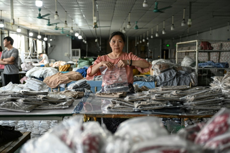 Une employée emballe des vêtements pour la société chinoise de commerce en ligne Temu, dans une usine à Canton, dans la province du Guangdong, le 16 avril 2025 dans le sud de la Chine ( AFP / JADE GAO )