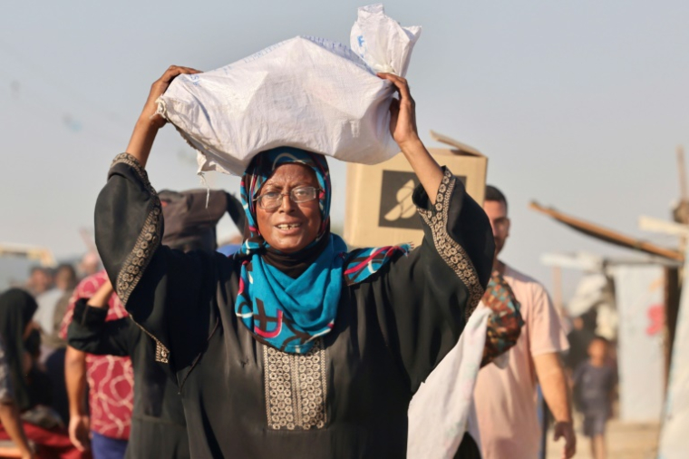 Une Palestinienne porte sur la tête un sac contenant des aides en retournant à al-Mawassi dans le sud de la bande de Gaza, le 24 juillet 2025 ( AFP / - )