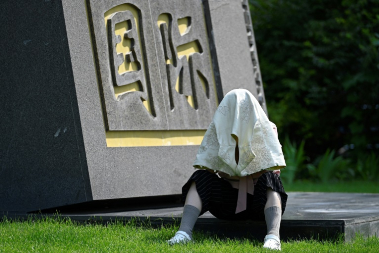 Une femme se protége du soleil alors qu'elle se repose devant un hôtel à Pékin, en Chine, le 23 juin 2025 ( AFP / WANG Zhao )