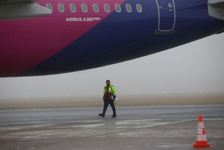 Un agent d'assistance au sol marche sur le tarmac près d'un Airbus A321neo de Wizz Air, immatriculé 9H-WMI, à l'aéroport de Varsovie-Modlin à Modlin.