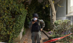Un membre des forces de sécurité israéliennes devant une maison frappée par un projectile à Shoham, dans le centre d'Israël, le 13 mars 2026 ( AFP / Ilia YEFIMOVICH )