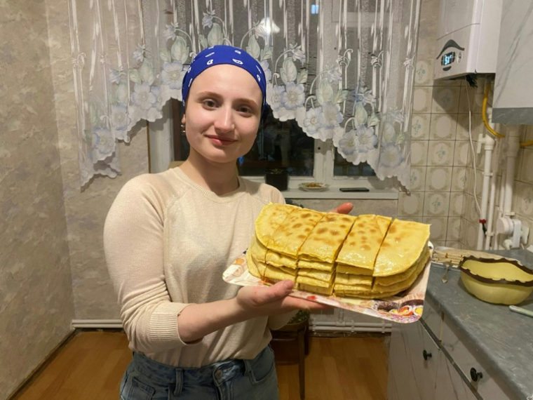 Photo diffusée le 27 janvier 2026 par une source connue de l'AFP montrant Aïchat Baïmouradova, le 1er mars 2025, présentant un plat traditionnel tchétchène qu'elle a préparé dans un endroit non divulgué en Arménie, où elle s'était réfugiée après avoir subi des violences familiales en Tchétchénie ( COURTESY OF ANONYMOUS SOURCE / - )