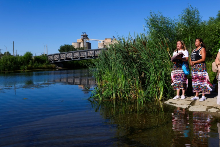 Les Manitou Mkwa Signers interprètent une chanson sur les rives de la rivière Don, dans le cadre du projet de protection contre les inondations des terrains portuaires de Toronto. ( AFP / Cole BURSTON )