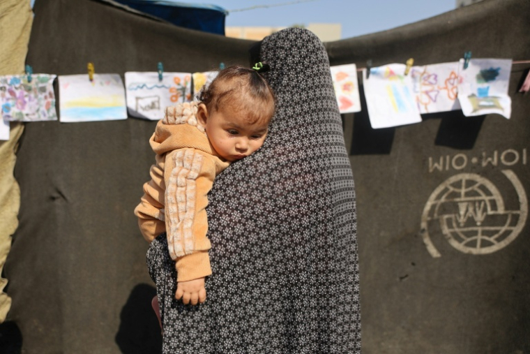 Une femme portant un enfant dans une école transformée en abri pour les Palestiniens déplacés dans le quartier d'Al-Rimal de la ville de Gaza, le 5 novembre 2025 ( AFP / Omar AL-QATTAA )