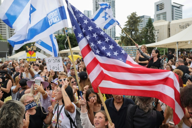 Des personnes agitent des drapeaux israéliens et américains sur la place des otages à Tel-Aviv le 9 octobre, après l'annonce d'un accord entre Israël et le Hamas ( AFP / Jack GUEZ )