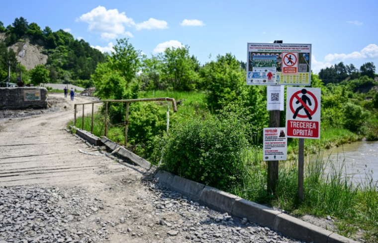 Panneaux "défense d'entrée" devant le pont enjambant la rivière Corund et menant à l'entrée de la mine de sel de Praïd, en Roumanie, le 3 juin 2025 ( AFP / Daniel MIHAILESCU )