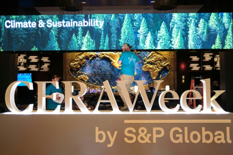 Deux hommes travaillent pour préparer le plus grand rendez-vous mondial des acteurs du pétrole, le 22 mars 2026 à Houston, au Texas ( AFP / RONALDO SCHEMIDT )