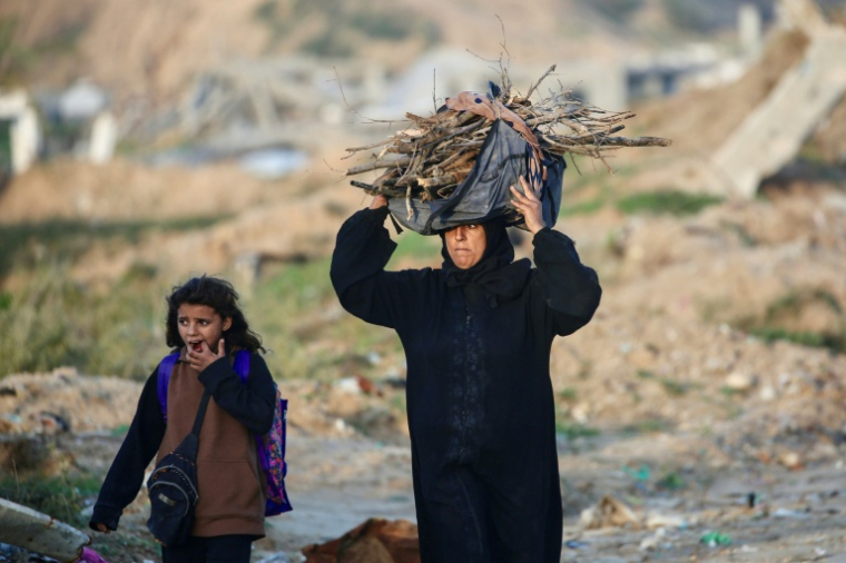 Une Palestinienne porte du bois dans le camp de Nousseirat, dans le centre de la bande de Gaza, le 31 décembre 2025 ( AFP / Eyad Baba )