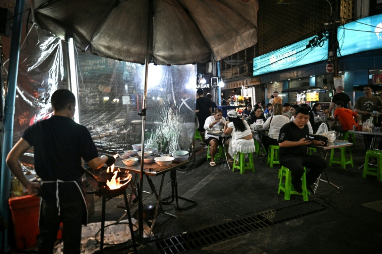 Des clients attablés dans un restaurant de rue, le 29 avril 2026 à Bangkok  ( AFP / Lillian SUWANRUMPHA )