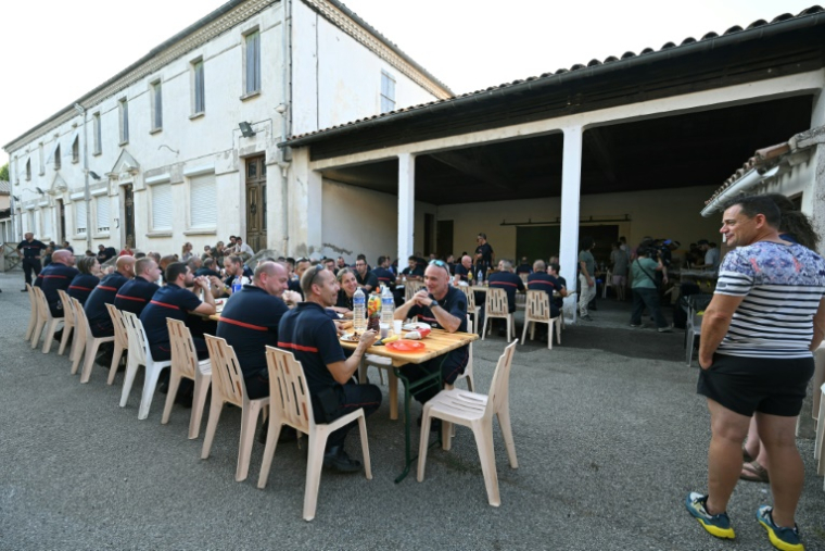 Les sapeurs-pompiers venus en renfort dans l'Aude lors d'un repas organisé en leur honneur à Talairan, dans l'Aude, le 8 août 2025 ( AFP / Bertrand GUAY )