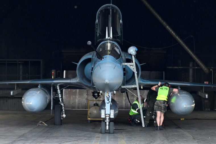 Des ingénieurs travaillent sur un avion Mirage 2000-5F de l'escadron de chasse "Cigognes" 1/2 (EC) dans un hangar de la base 116 de l'armée de l'air française à Luxeuil-les-Bains, le 27 mai 2025 en Haute-Saône ( AFP / Jean-Christophe VERHAEGEN )