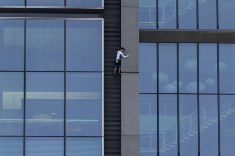 Le grimpeur français Titouan Leduc escalade à mains nues et sans protection la Varso Tower, le plus haut gratte-ciel de l'Union européenne, à Varsovie, le 27 septembre 2025 en Pologne ( AFP / Wojtek RADWANSKI )