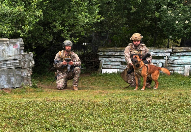 Des maîtres-chiens s’apprêtent à lancer un drone qui guidera Peyo, un berger belge malinois du Commando parachutiste de l’Air 20 (CPA20), à la recherche d’explosifs lors d’une démonstration sur la base aérienne de Vélizy-Villacoublay, le 28 mai 2025 dans les Yvelines ( AFP / Mathieu RABECHAULT )