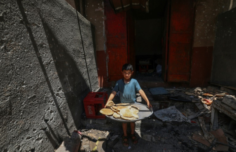 Un garçon palestinien sort avec du pain d'une boulangerie de fortune touchée par des frappes israéliennes dans le camp de réfugiés de Nusseirat, dans le centre de la bande de Gaza, le 8 mai 2025 ( AFP / Eyad BABA )