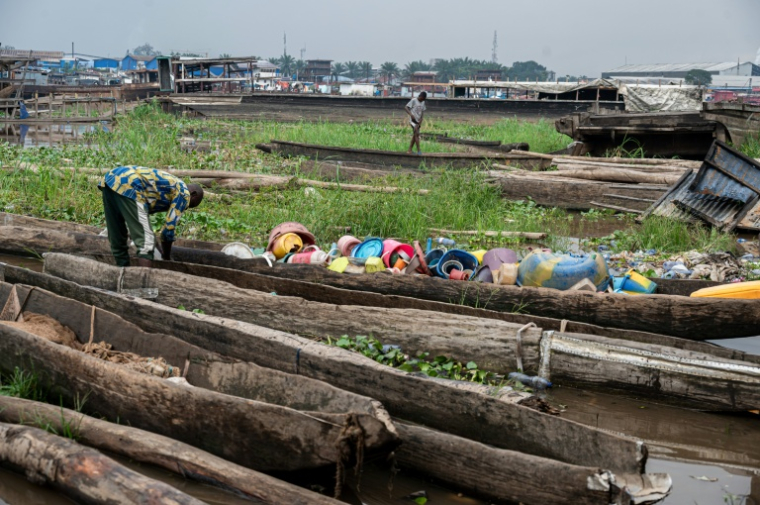Un pêcheur trie dans une pirogue des objets en plastique ramassés sur les rives du fleuve Congo à Kinshasa, le 27 avril 2026 en RDC ( AFP / Hardy BOPE )