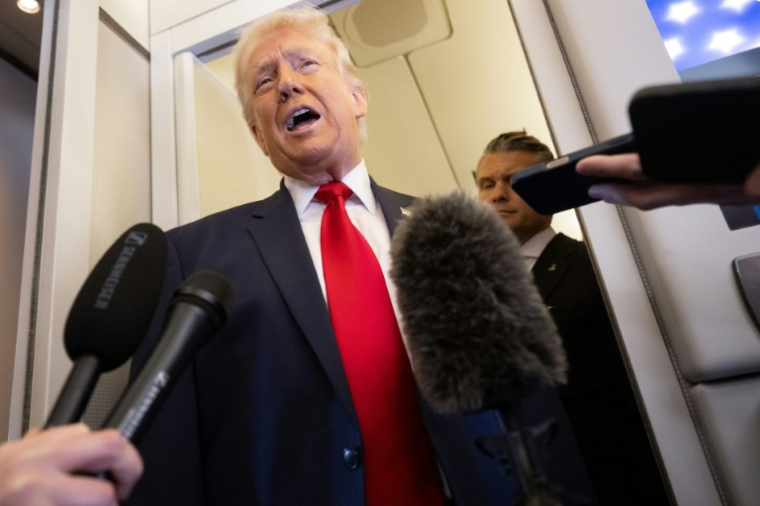 Le président américain Donald Trump parle à la presse, avec son ministre de la Défense Pete Hegseth dans son dos, à bord de l'avion présidentiel Air Force One en direction de Miami, le 7 mars 2026 ( AFP / SAUL LOEB )