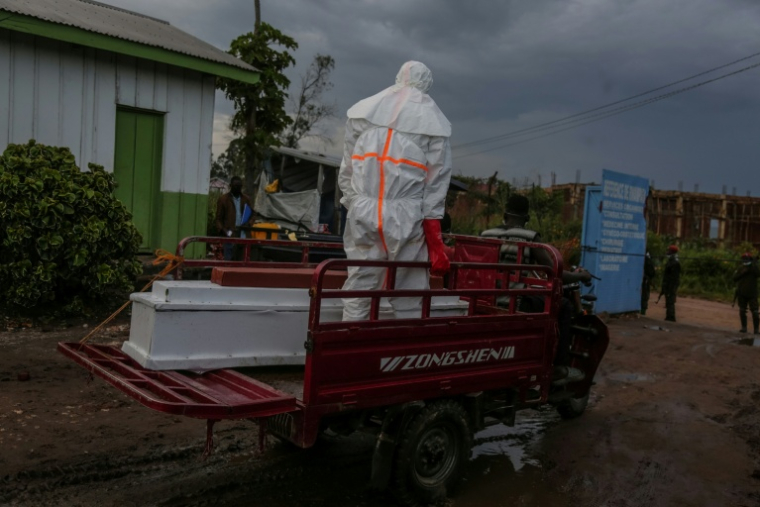 Un membre du personnel médical en combinaison de protection accompagne vers le cimetière le cercueil d'un patient décédé ,à l'hôpital de Rwampara, lors de l'épidémie d'Ebola, le 21 mai 2026 en RDC ( AFP / Seros MUYISA )