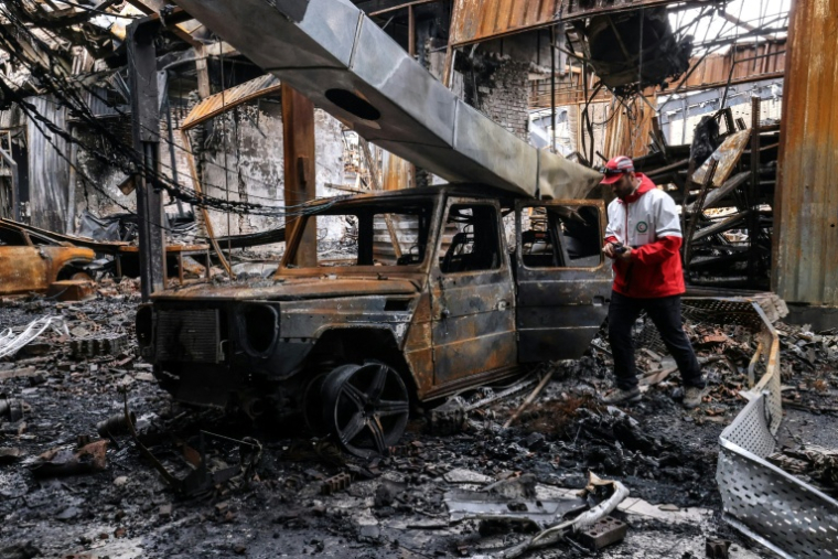 Un membre du Croissant-Rouge iranien dans les décombres d'un centre de services automobiles frappé par un tir de missile, à Téhéran le 28 mars 2026 ( AFP / ATTA KENARE )