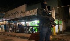 Un policier surveille un bar et magasin d'alcool où une attaque armée contre des civils a eu lieu près de la ville d'El Empalme, Équateur, le 28 juillet 2025 ( AFP / Gerardo MENOSCAL )