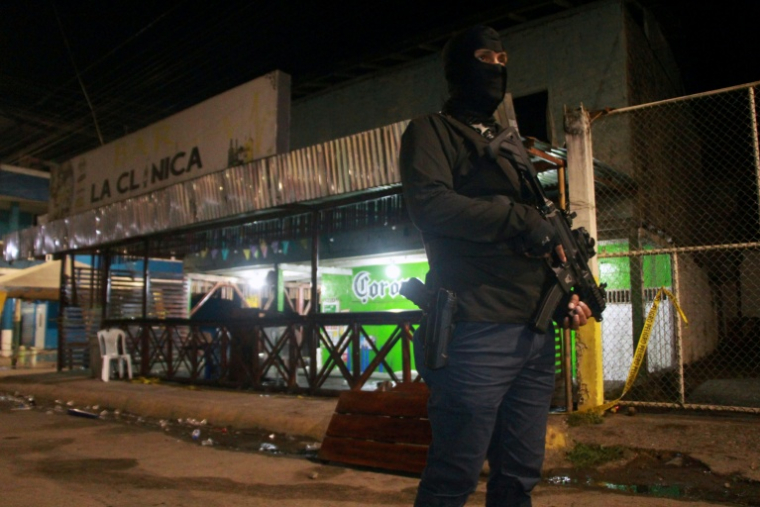 Un policier surveille un bar et magasin d'alcool où une attaque armée contre des civils a eu lieu près de la ville d'El Empalme, Équateur, le 28 juillet 2025 ( AFP / Gerardo MENOSCAL )