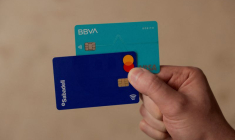 Un homme montre ses cartes de débit des banques BBVA et Sabadell