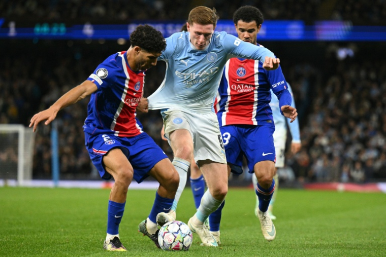 Elliot Anderson (C) de Manchester City aux prises avec Warren Zaire-Emery (D) et Achraf Hakimi (G) lors de la victoire du Paris SG 4-2 sur la pelouse de Manchester City, le 14 octobre 2026 ( AFP / Oli SCARFF )