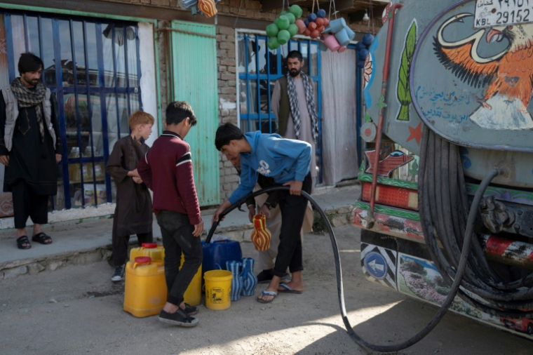 Des jeunes Afghans remplissent des bidons d'eau potable à partir d'un camion-citerne, le 27 avril 2025 à Kaboul ( AFP / Wakil KOHSAR )