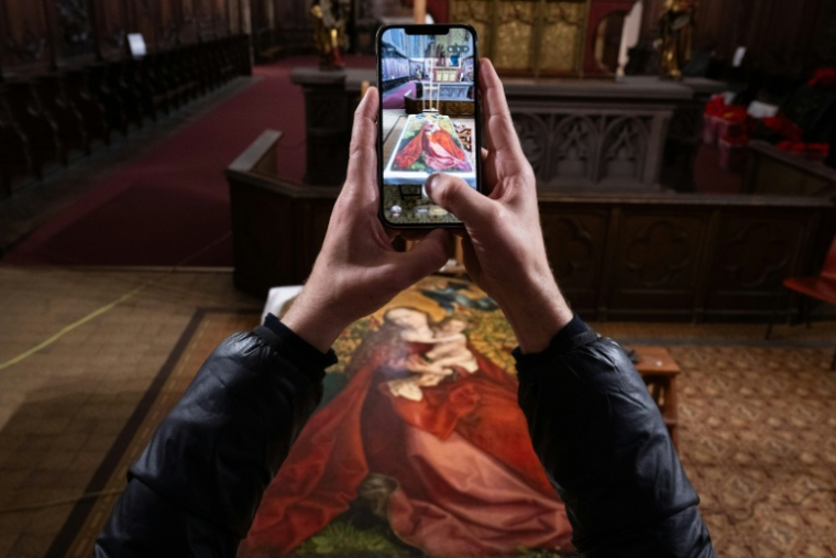 Un visiteur prend une photo de la restauration de "La Vierge au buisson de roses" peinte par Martin Schongauer en 1473, à l'église des Dominicains de Colmar, le 5 mars 2026 dans le Haut-Rhin ( AFP / SEBASTIEN BOZON )