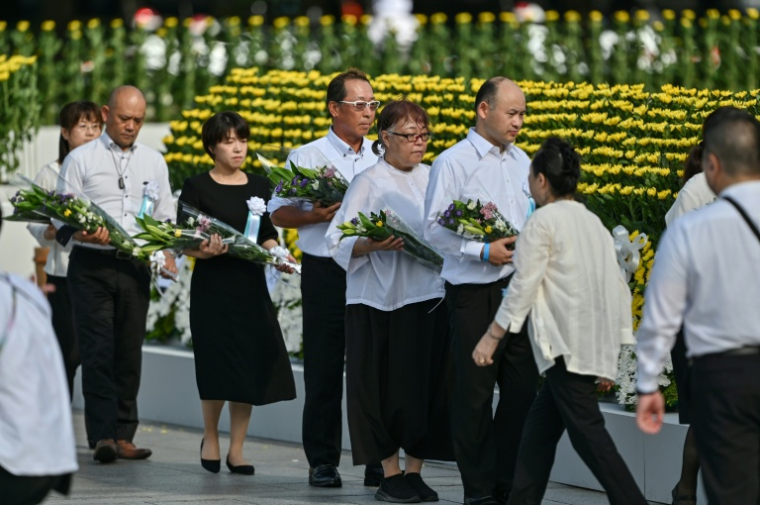 Des invités attentent de pouvoir déposer un bouquet de fleurs au niveau du cénotaphe commémorant le bombardement atomique de 1945, le 6 août 2025 à Hiroshima au Japon ( AFP / Richard A. Brooks )