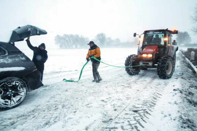 Un agent municipal s'apprête à tracter une voiture piégée par la neige, le 7 janvier 2026 à Sebourg, dans le Nord ( AFP / Francois LO PRESTI )