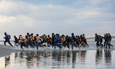 Des migrants courent pour embarquer à bord d'un "small boat", le 12 août 2025 à Gravelines, dans le Nord ( AFP / Sameer Al-DOUMY )